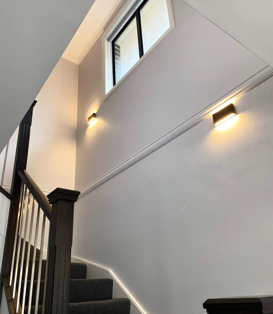 Modern staircase with wall lights and window.