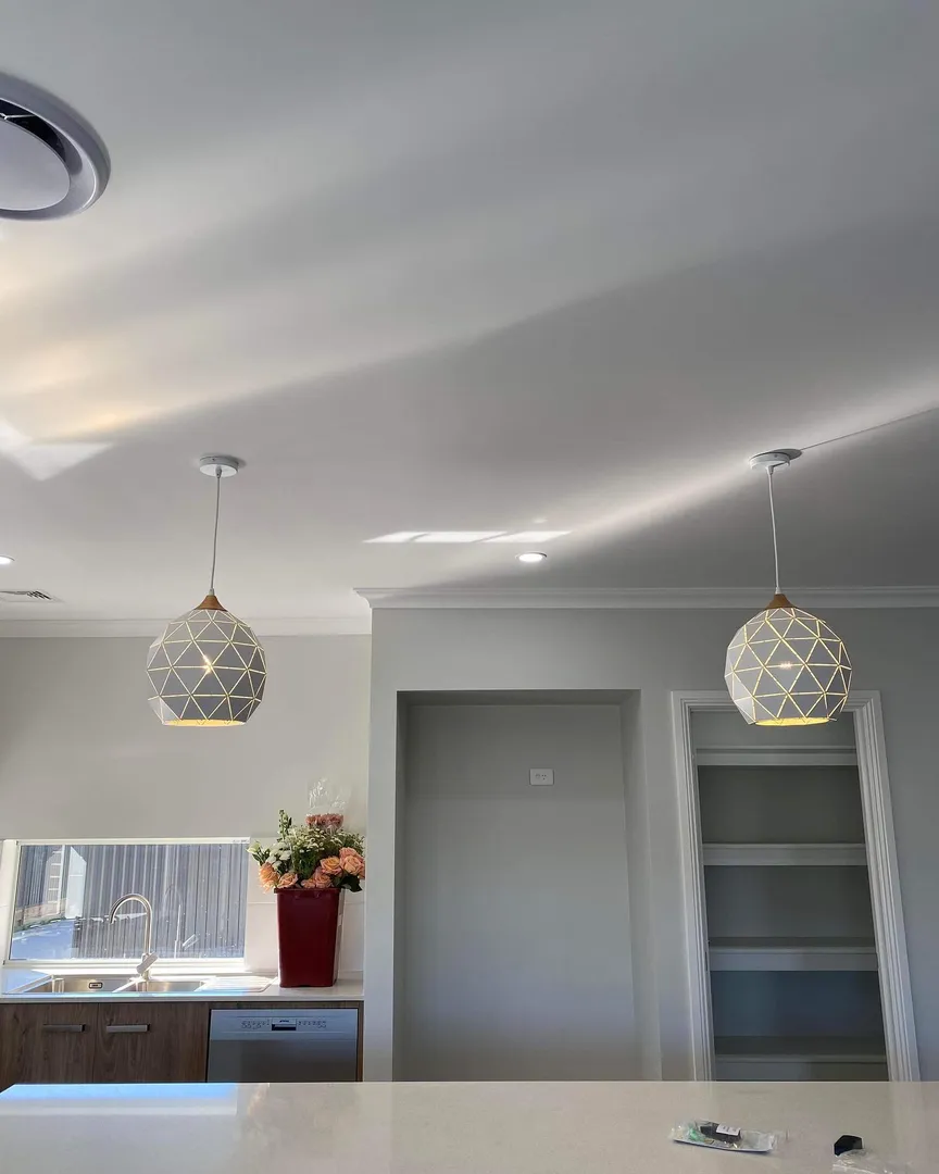 Modern kitchen with pendant lights and flowers.
